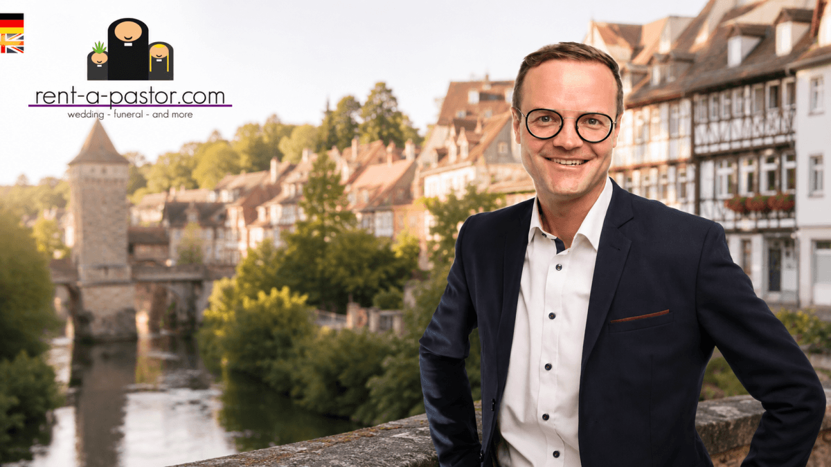 Trauredner Benjamin Bürger in modernem dunkelblauen Anzug vor historischer Kulisse von Schwäbisch Hall mit Fachwerkhäusern und Kocher.