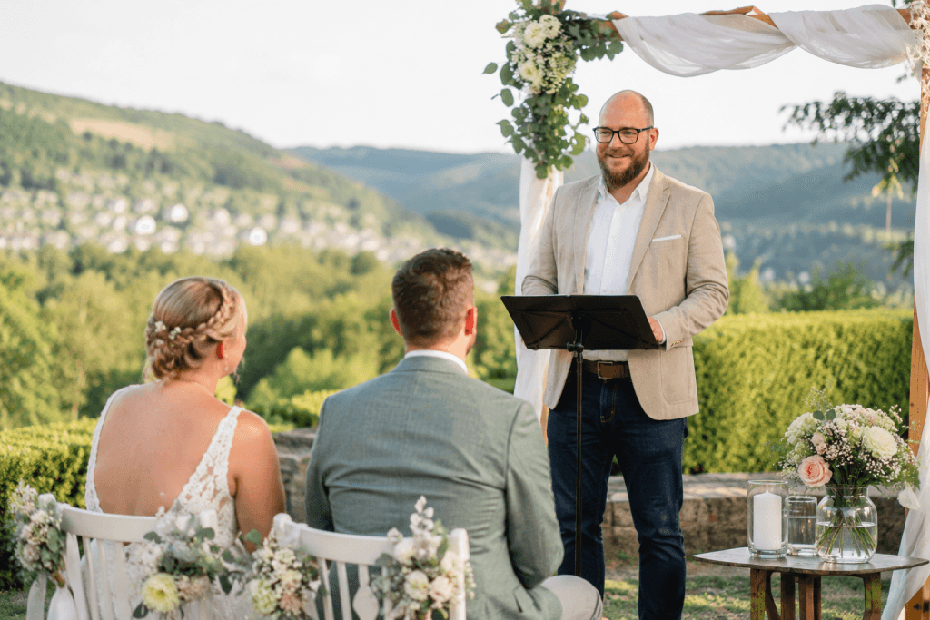 Trauredner Simon Birr begleitet ein Brautpaar bei einer freien Trauung in Mittelhessen mit Blick über die Hügellandschaft des Lahn-Dill-Kreises
