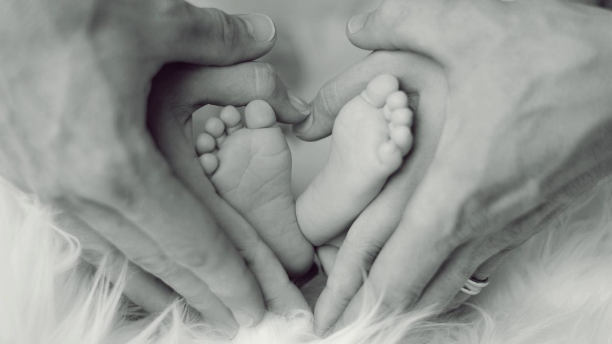 Ein glückliches Neugeborenes wird von seinen Eltern zärtlich gehalten. Die stolzen Eltern umarmen ihr Baby.