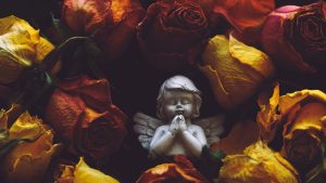 Inmitten von Blättern steht ein Engel – eine visuelle Metapher für die Freiheit und persönliche Gestaltung einer 'Freien Beerdigung'.