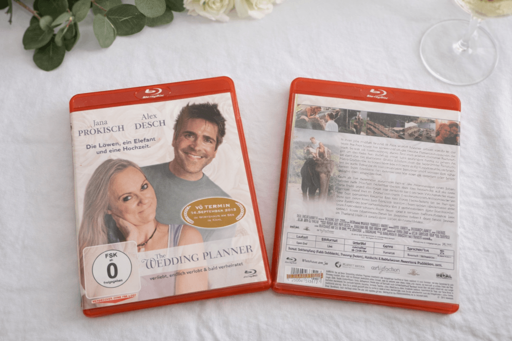 Blu-ray-Hochzeitseinladung mit gestalteter Vorder- und Rückseite liegt auf weiß gedecktem Tisch, kreative Einladung im Filmstil für eine freie Trauung