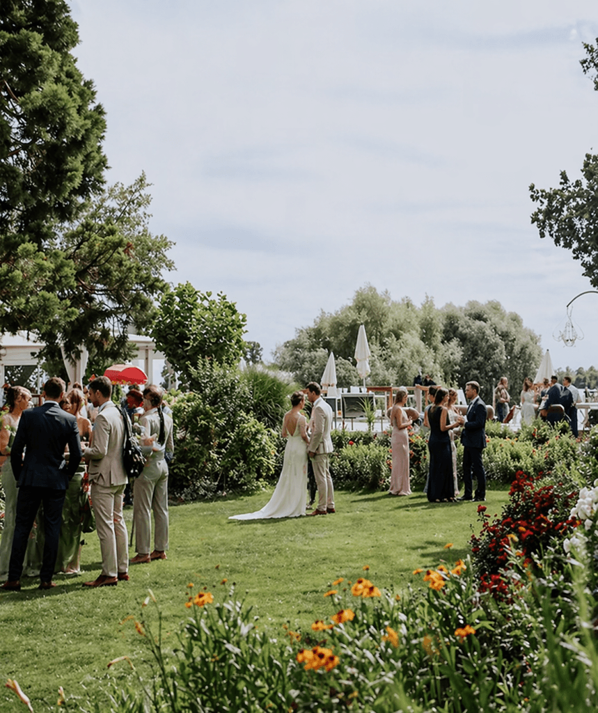 Hochzeitsgesellschaft im Garten auf der Insel Nonnenau nahe dem Steg, Gäste stehen zusammen und feiern eine freie Trauung